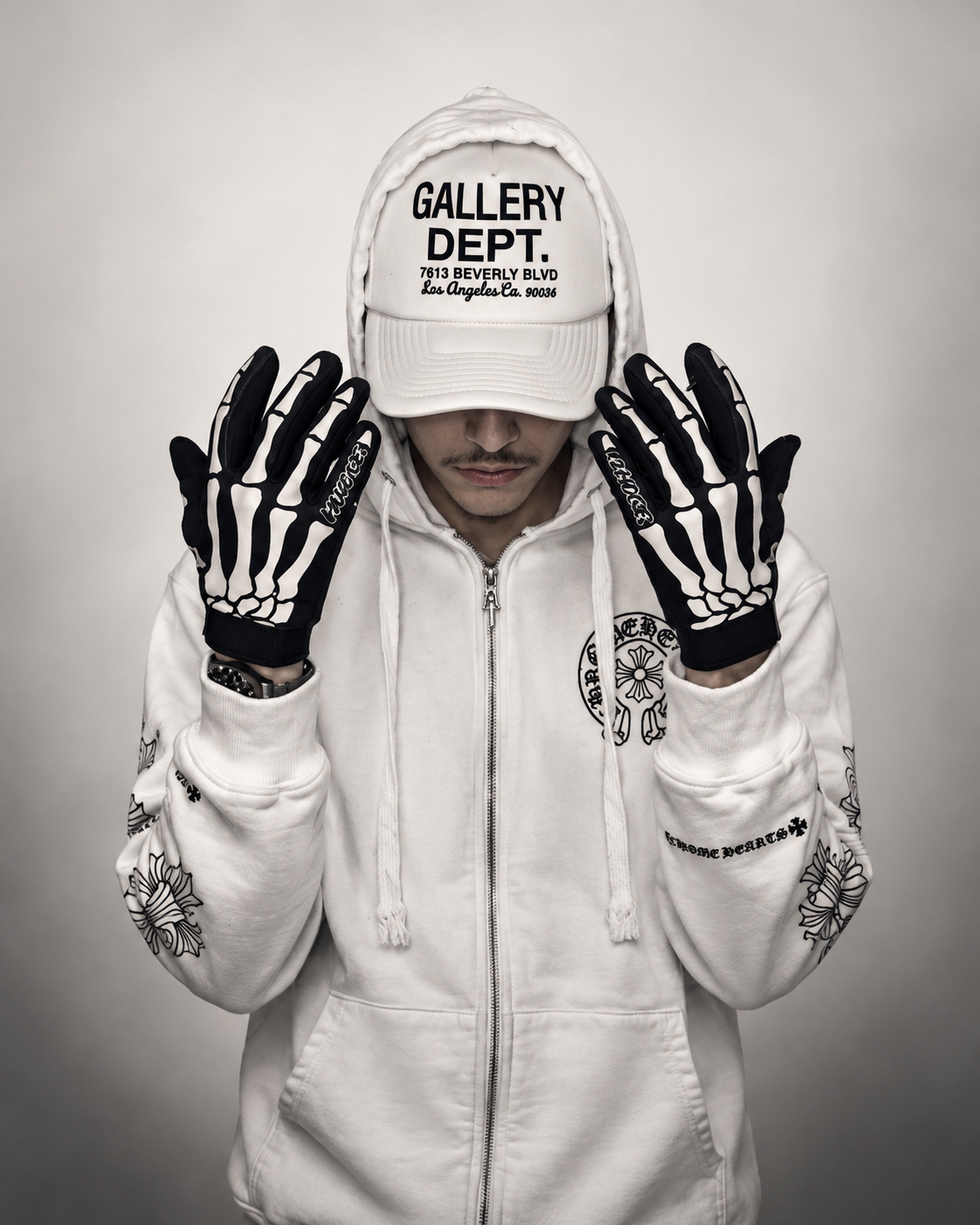 Elicit Abandz in a white hoodie and cap, wearing black skeleton gloves